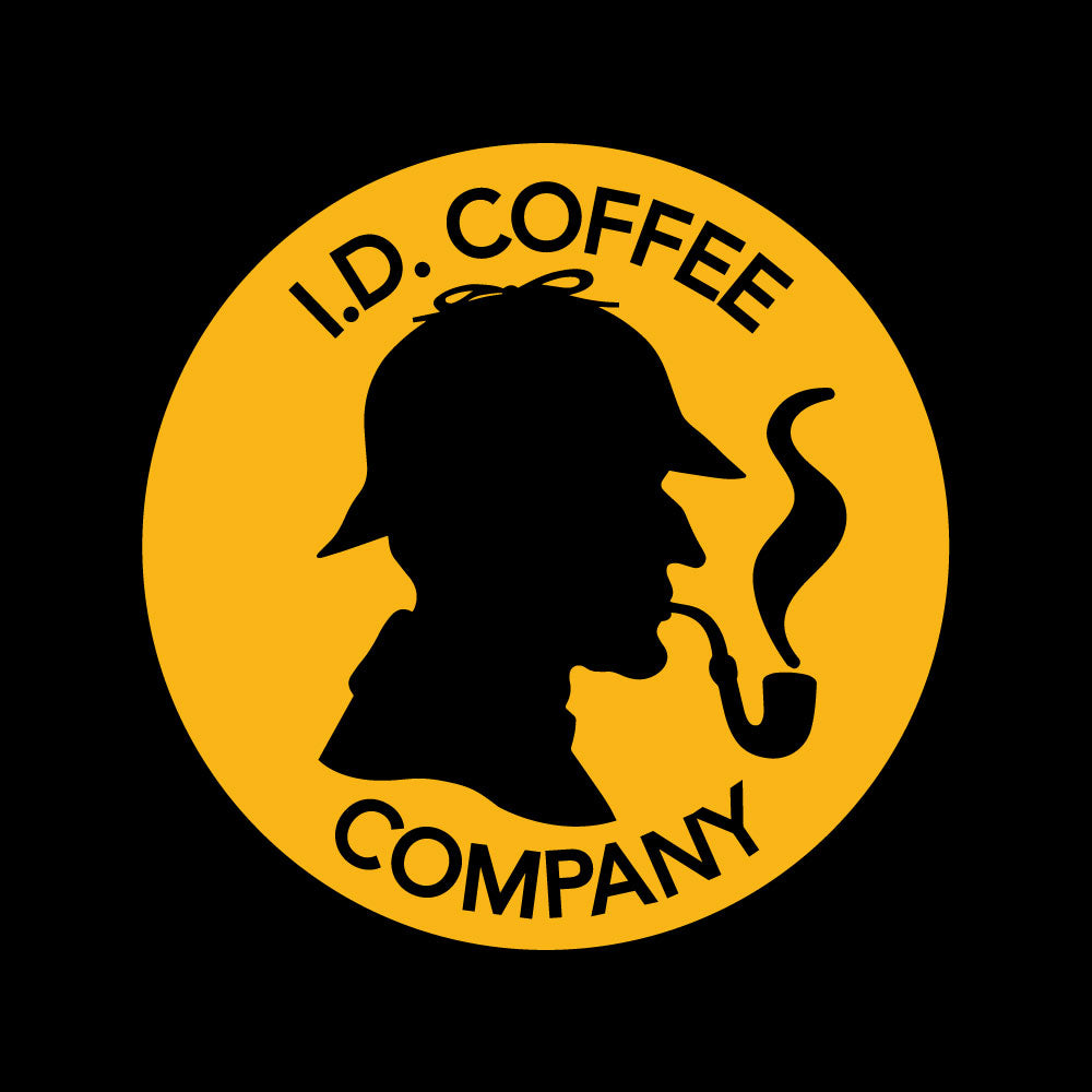 Yellow Circular I.D. Coffee Co Logo with Black Silhouette of Investigator with Deerstalker Hat and Smoking Pipe in Center on Black Background "I.D. COFFEE" text above Silhouette, "COMPANY" Under Silhouette